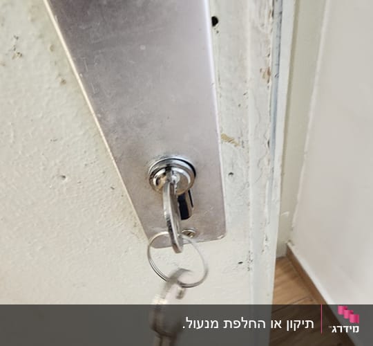 מנעול עם מפתח תלוי על דלת מתכת